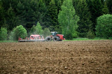 Büyük bir traktör ve saban, mahsul ekilmeden önce tarlayı sürüyorlar. Bir traktör tarla boyunca sürüp ekilebilir araziyi düzleştirir..