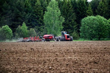 Büyük bir traktör ve saban, mahsul ekilmeden önce tarlayı sürüyorlar. Bir traktör tarla boyunca sürüp ekilebilir araziyi düzleştirir..