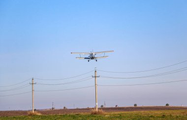 Arazi gübreleri ve böcek ilaçları için özel bir difüzörü olan küçük bir çift kanatlı uçak hız kazanır ve sonbahar tarlasında havalanır..