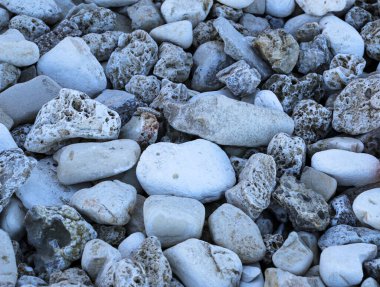 Nehir kıyısında taş çakıl taşı plajı. Çakıl taşlarının, çakıl taşlarının ve taşların doğal arka planı farklı şekillerde, renklerde ve dokularda.