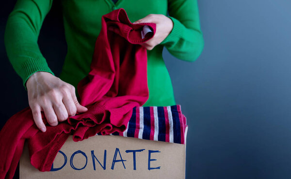 Donation Concept. Woman Preparing her Used Old Clothes into a Donate Box