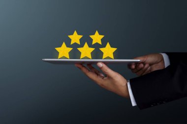 Customer Experience Concept. Businessman Holding a digital tablet to Present Five Star Rating on Satisfaction Survey, Side view, Dark tone clipart