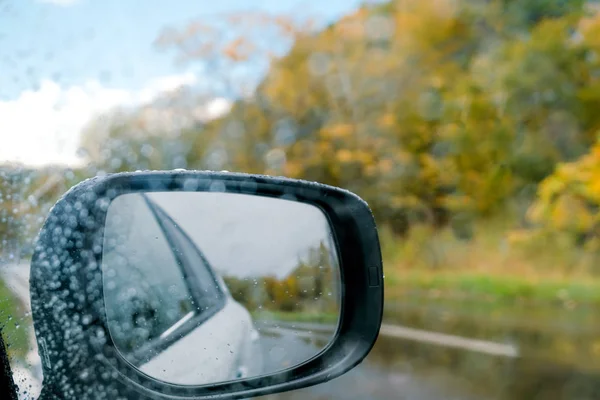 雨の日をドライブします 秋のシーズンで道で天気が悪い サイドミラー ドライバーの位置からスナップします — ストック写真