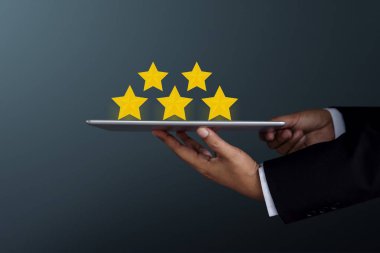 Müşteri deneyimi kavramı. Dijital bir tablet üzerinde memnuniyet anketi, yan görünüm, koyu tonu mevcut 5 Star Rating tutan işadamı