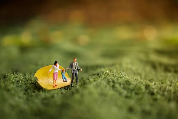 Happy Family Concept. Miniature Figures of Father, Mother and Son Walking in Outdoor Park to Making Activities together
