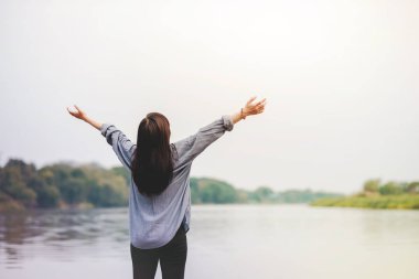 Hayat i. Taze hava solumak için silah yükselterek nehrin yanında duran mutlu kadın. Tatil eğlence ve rahatlatıcı yaşam tarzı