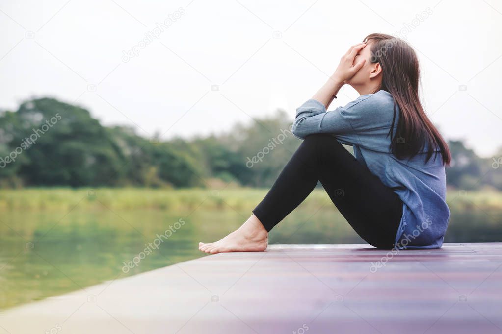 Bad Day Concept. Sad Woman Sitting by the River on Wooden Patio Deck. Faceless with Full Length Body, Side View