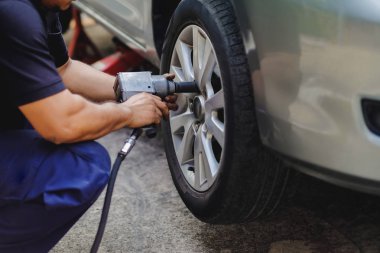 Lastik değiştirme kavramı. Makinist garaj içinde tekerlek fındık için elektrikli tornavida anahtarı kullanarak. Araba bakım ve servisler
