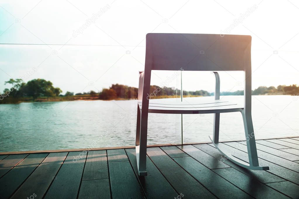 Life Unpluged Concept. Relaxing by the River. Empty Armchair on Wooden Patio Deck. Holidays Leisure and Relaxing Lifestyle. Vintage Filter 