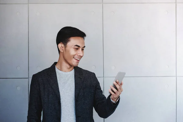 Portret Młodego Biznesmena Szczęśliwy Pomocą Smartfonu Stojących Przemysłowe Betonowe Ściany — Zdjęcie stockowe