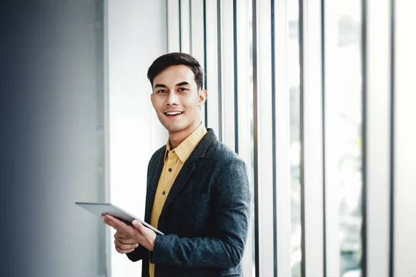 Retrato del hombre de negocios feliz parado junto a la ventana en el cargo . — Foto de Stock