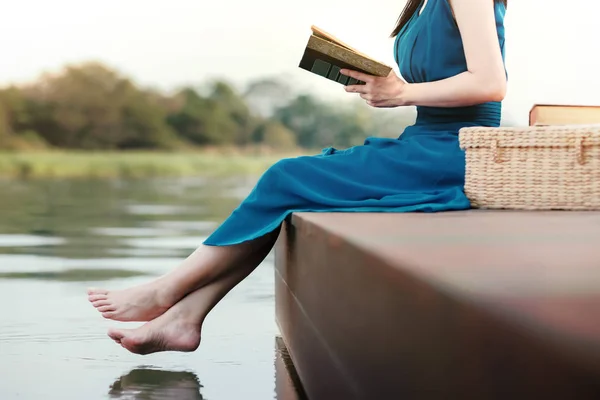 Молода жінка розслабляючий за Riverside. Сидячи на палубі і читання B — стокове фото