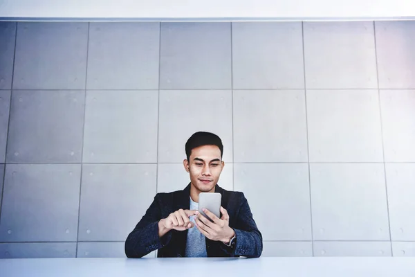 Feliz joven empresario asiático trabajando en Smartphone. Sonriendo y — Foto de Stock