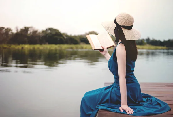 Молода жінка розслабляючий за Riverside. Сидячи на палубі і читання B — стокове фото