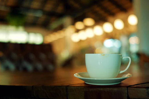 Кофейная чашка на столе в кафе. Blurred Lights in bar as backgr — стоковое фото