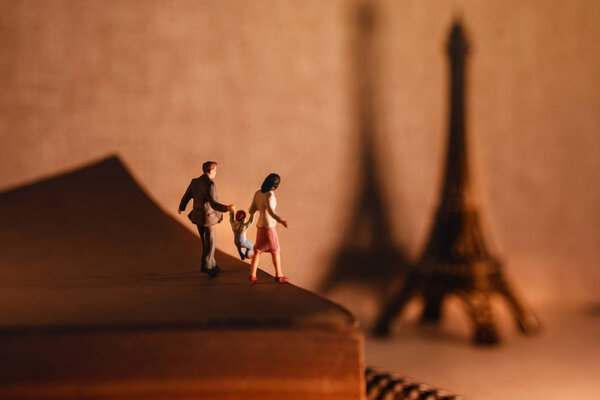 Dream Destination for Vacation. Travel in Paris, France. a Miniature Tourist Family Standing on the Aged Book. the Eiffel Tower as background. Warm Tone