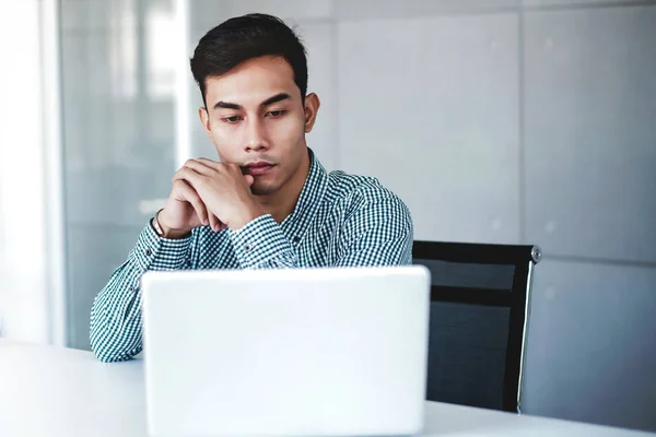 Empresario serio joven que trabaja en la computadora portátil en la oficina — Foto de Stock