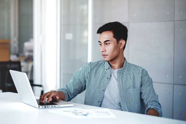 Seriously Young Businessman Working on Computer Laptop in Office