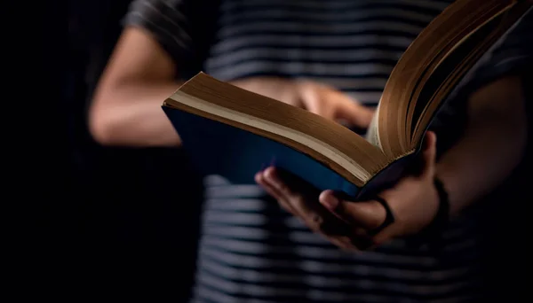 Concetto di lettura. Persona che tiene aperto il libro della Bibbia a portata di mano. Scuro — Foto Stock