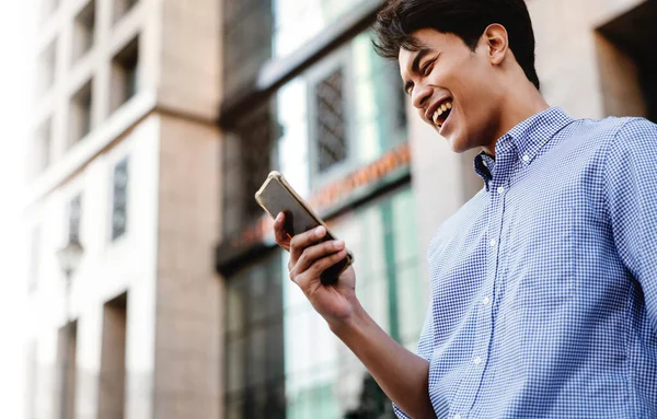 Χαμογελαστός Νεαρός Ασιάτης Επιχειρηματίας Χρησιμοποιώντας Κινητό Τηλέφωνο Στην Πόλη — Φωτογραφία Αρχείου