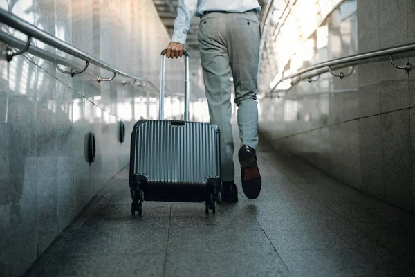 Low Section of Passenger Businessman Walking with Suitcase at the Walkway in Airport. Focus on Luggage. Low Angle View