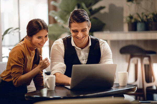 Молодая пара, работающая вместе над ноутбуком в кафе. Многонациональная мотивированная командная работа. Счастливые бизнесмены