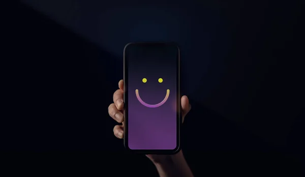 Customer Experiences Concept. Hand Holding  a Mobile Phone with Smiling Face Emoticon. Happy Customer giving a Positive Review Feedback. Client Satisfaction Surveys