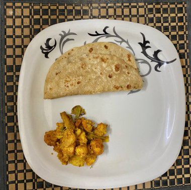 Roti ve karışık sebze yemeği tabakta servis edilmeye hazır.