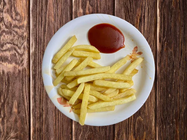 Patates kızartması ve domates sosu tabakta servis ediliyor.