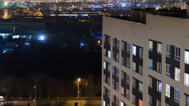 きらめく窓のライトが付いている高層モダンな建物の夕方の時間 カジュアルな都会の生活 道路上のトラフィック タワー屋上から 工場やコンテナのクレインを備えた工業地域 — ストック動画