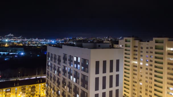 夜の都市のタイムラプス 居住の高層ビルと小さな建物との広角パノラマ 道路の信号がぼやけていた 背景に工業地帯のパイプ — ストック動画