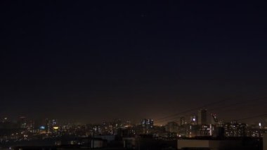 Gece şehir silueti timelapse. Kule çatıdan modern şehrin üst hava panoramik görünümü. Pencerelerde ışıklar titriyor. Constraction sitesini yakınlaştıran video