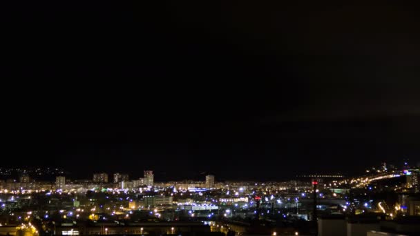 Night city skyline timelapse.Top aerial panoramic view of modern city from tower rooftop. Road junction traffic. Lights flicker in windows.Residential flats of dormitory area close to industrial zone — Stock Video