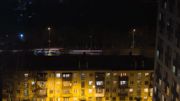 Abend Timelase eines Gebäudes mit Menschen Silhouetten in den Fenstern. lässiges urbanes Stadtleben. Verkehr auf der Straße. Menschen warten an einer Bushaltestelle mit Ampel. Antennenpanorama vom Turmdach — Stockvideo