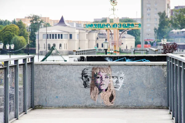 俄罗斯加里宁格勒 - 2015年9月14日：身份不明的艺术家的街头艺术。一个女人的脸，男人和头骨，街头壁画。背景有池塘的公园 — 图库照片