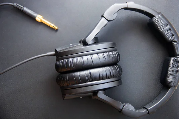 Equipo musical, auriculares negros de estudio profesional y cable de conexión. Vista desde arriba —  Fotos de Stock