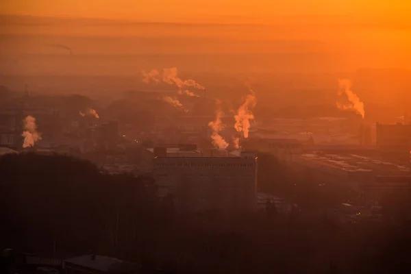 工業地帯の工場の上の日の出。オレンジ色の光線は、朝の霧とパイプからの煙を通して来ます。工業用化学品製造 — ストック写真