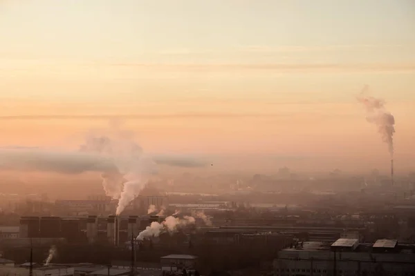 Nascer do sol sobre a fábrica na área industrial. Névoa da manhã e fumo dos canos. Poluição do ar, problemas ecológicos na cidade grande — Fotografia de Stock