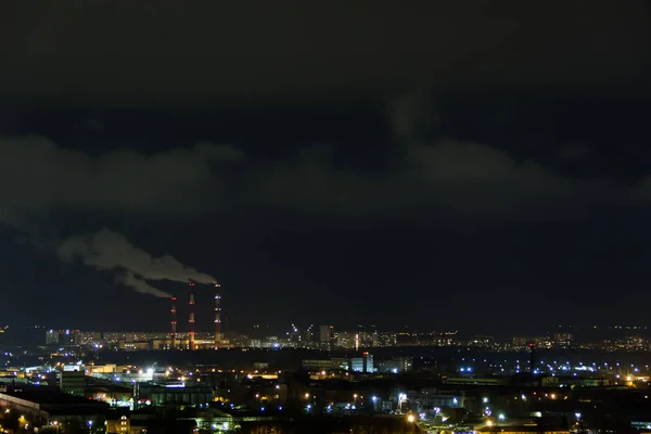 Skyline cidade à noite.Vista noturna de um bairro com baixo edifício blocos de apartamentos iluminado luzes da janela. Tubos de fumaça de usina térmica — Fotografia de Stock