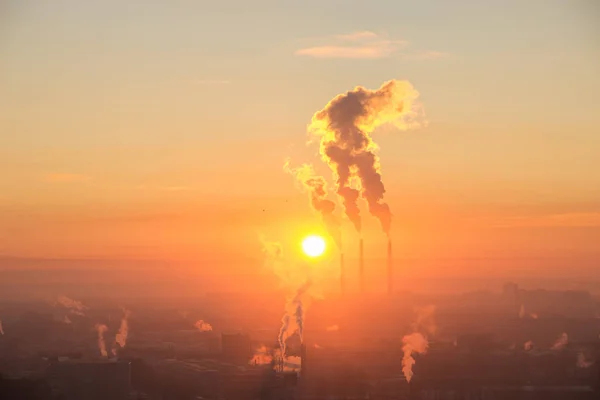 O sol vermelho nasce no horizonte sobre a cidade industrial. Fumaça proveniente dos tubos da usina térmica. Fotografia aérea do nascer do sol sobre a zona industrial da cidade — Fotografia de Stock