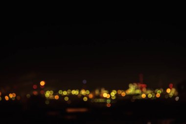 Geceleri şehir silueti. Düşük katlı apartman blokları ışıklı pencere ışıkları ile bir mahallenin gece görünümü. Termik santral duman boruları. Sanayi bölgesinin bulanık soyut görüntüsü