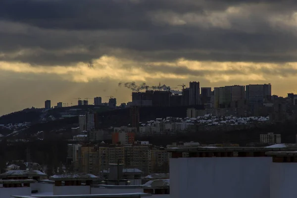 Construction cranes on new residential areas. Building new city on the edge of a high hill. Sunny cloudy day. Sun beams through heavy clouds — Stock Photo, Image