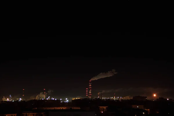 Vue de nuit de la raffinerie de pétrole sur l'horizon de la ville. Beaucoup de lumières. Zone industrielle et résidentielle. Pollution de l'air et changement climatique. Fumée provenant des tuyaux de l'usine — Photo