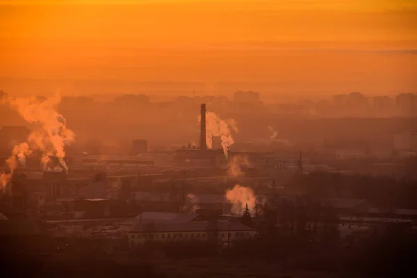 工業地帯の工場の上の日の出。オレンジ色の光線は、朝の霧とパイプからの煙を通して来ます。工業用化学品製造 — ストック写真