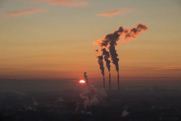 市内の工業地帯の日の出の航空写真。赤い太陽が合う.火力発電所のパイプから煙が出る — ストック写真