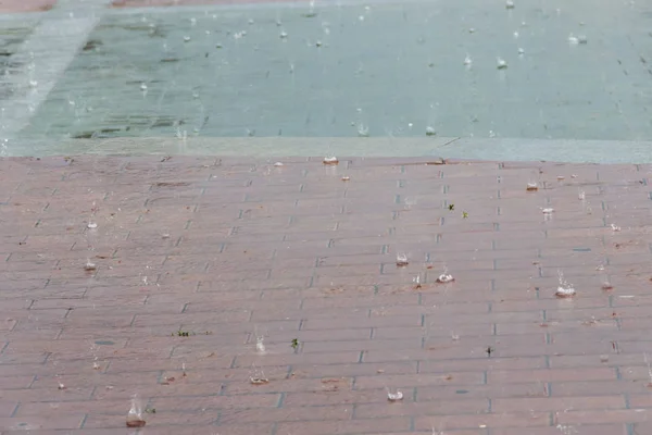 Капли дождя капают в луже с отражением — стоковое фото