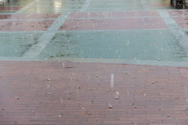 Gotas de chuva ondulando em uma poça com edifícios e reflexão do céu — Fotografia de Stock