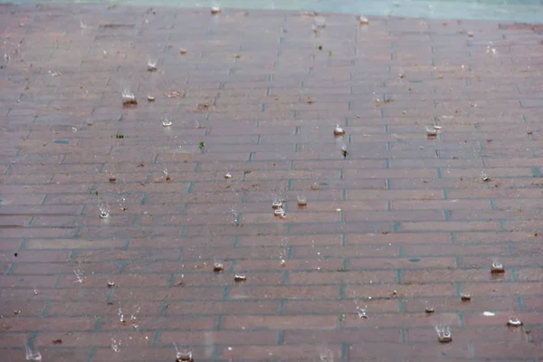 Капли дождя капают в луже с отражением — стоковое фото