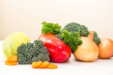 Beyaz masada su damlaları ile farklı sebze ve taze otlar. Havuç ve brokoli lahanası Portakal dilimleri