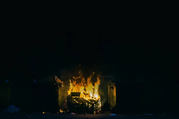 Burning trash container and old wood chair with other garbage close up. Plastic garbage can has almost fused — Stock Photo, Image